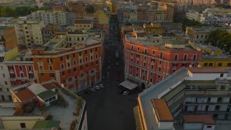 Aerial-descending-footage-of-crossroad-among-blocks-of-houses-in-city.-Forwards-fly-above-street.-Rome,-Italy