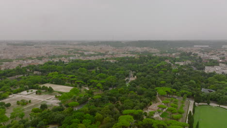 Aerial-panoramic-view-of-large-city-on-cloudy-day.-Forwards-fly-above-park-with-green-trees-and-equestrian-complex.-Rome,-Italy