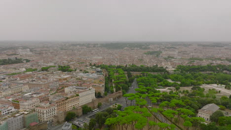Aerial-footage-of-green-trees-in-park-and-buildings-in-metropolis.-Historic-urban-borough-under-overcast-sky.-Rome,-Italy
