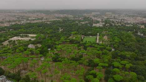 Aerial-panoramic-view-of-large-park-in-city-on-cloudy-day.-Fly-high-above-grown-trees-in-Villa-Borghese-park.-Rome,-Italy