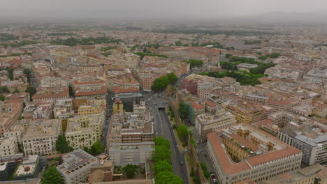 Trunk-road-leading-through-urban-borough.-Aerial-view-of-blocks-on-multistorey-buildings-in-city-on-cloudy-day.-Rome,-Italy