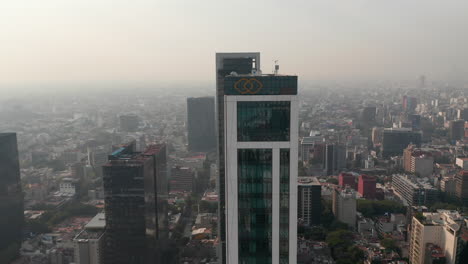 Hazy-aerial-view-of-downtown-cityscape.-Low-drone-flyover-of-tall-office-building.-Mexico-city,-Mexico.