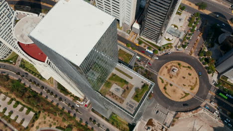 Fly-over-modern-tall-Paradox-Torre-building.-Camera-tilt-down-shot.-Top-down-view-of-surrounding-streets-and-park.-Mexico-City,-Mexico.
