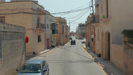 Lonely-Car-in-Empty-Ghost-Town,-mediterranean-Houses-in-Beige-and-Brown-Color-on-Malta-Island-during-Coronavirus-Covid-19-Pandemic-and-Lockdown,-slow-Aerial-Dolly-forward