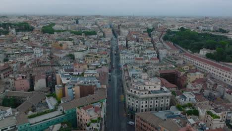 Forwards-fly-above-street-surrounded-by-residential-buildings-in-city-centre.-Metropolis-on-cloudy-day.-Rome,-Italy