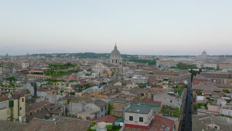 Fly-above-buildings-in-city-centre-at-twilight.-Various-old-residential-houses-in-urban-thorough.-Church-towers-protruding-above-other-rooftops.-Rome,-Italy