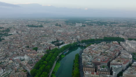 Aerial-footage-of-Tiber-river-bending-through-historic-city-centre.-Rows-of-lush-green-trees-on-riverbanks.-Rome,-Italy