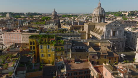 Forwards-fly-above-old-buildings-with-green-plants-on-rooftop-terraces.-Churches-and-old-tourist-sights.-Rome,-Italy