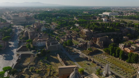 Aerial-view-of-famous-ancient-roman-tourist-sights.-Remains-of-old-temples-and-buildings,-Colosseum-in-background.-Rome,-Italy