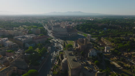 Historic-tourist-sights-against-sun.-Aerial-panoramic-view-of-ancient-landmarks,-Colosseum-amphitheatre-and-remains-of-very-old-sites.-Rome,-Italy
