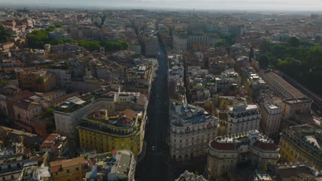 Aerial-panoramic-footage-of-historic-urban-borough.-Forwards-fly-above-street-and-tilt-down-on-Piazza-Barberini-with-Fontana-del-Tritone.-Rome,-Italy