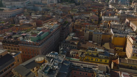 High-angle-view-of-buildings-in-urban-borough,-backwards-fly-and-tilt-up-reveal-of-cityscape-with-famous-landmarks.-Rome,-Italy