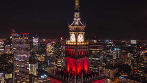 Pull-back-footage-of-top-of-historic-tall-building-tower.-Hyperlapse-of-colourful-night-cityscape.-Warsaw,-Poland