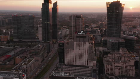 Tilt-up-reveal-of-group-of-tall-modern-downtown-skyscrapers-against-colourful-sunset-sky.-Warsaw,-Poland