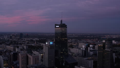 Descending-footage-of-modern-high-rise-office-buildings-towering-high-above-surrounding-urban-development.-Warsaw,-Poland