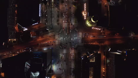 Aerial-birds-eye-overhead-top-down-panning-view-of-cars-starting-at-intersection-on-green-light.-Traffic-in-night-city.-Warsaw,-Poland