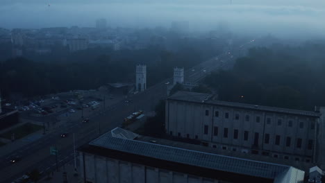 Slide-and-pan-shot-of-foggy-morning-scene.-Cars-driving-on-multilane-road-near-railway-track-in-urban-neighbourhood.-Warsaw,-Poland