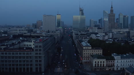 Forwards-fly-above-wide-street.-Panoramic-view-of-downtown-skyscrapers.-Blue-toned-morning-shot.-Warsaw,-Poland