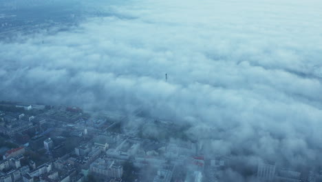 Aerial-panoramic-footage-of-morning-city-shrouded-in-fog.-Visible-buildings-in-urban-neighbourhood-and-top-of-tower-on-cable-stayed-bridge-over-Vistula-river.-Warsaw,-Poland