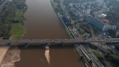High-angle-view-of-heavy-traffic-on-waterfront-road-and-bridge-spanning-Vistula-river.-Vehicles-driving-in-city.-Warsaw,-Poland