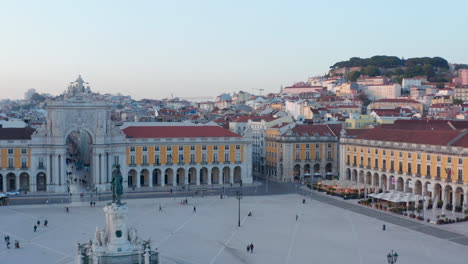 Aerial-ascending-view-of-people-on-Praca-do-Comercio-public-square-in-Lisbon-with-Arco-da-Rua-Augusta-and-residential-houses-in-the-background