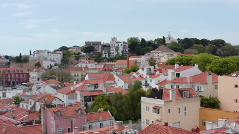 Slow-aerial-dolly-in-view-of-luxury-traditional-colorful-houses-on-the-hills-surrounding-dense-urban-city-center-of-Lisbon,-Portugal