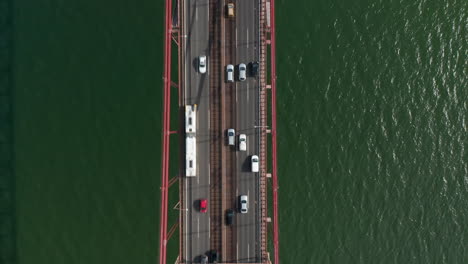 Aerial-birds-eye-overhead-top-down-view-of-heavy-traffic-on-multilane-road-in-rush-hour.-Highway-bridge-over-rippled-water-from-drone-camera.-Lisbon,-capital-of-Portugal.