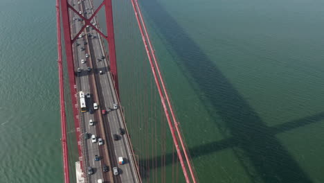 Aerial-slider-front-view-of-dense-multi-vehicle-traffic-across-famous-large-red-suspension-Ponte-25-de-Abril-bridge-in-Lisbon,-Portugal
