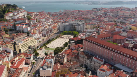 Aerial-orbit-of-Lisbon-city-center-with-traditional-colorful-houses-around-Martim-Moniz-square,-Lisbon-castle-on-the-hill-and-sea-in-the-background