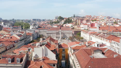 Aerial-view-of-historic-town-center,-King-Pedro-IV-Square-with-Column-of-Pedro-IV-and-Queen-Maria-II-National-Theatre.-Drone-camera-flying-forward-and-tilts-down.-Lisbon,-capital-of-Portugal.