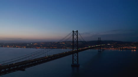 Aerial-view-of-car-traffic-across-the-sea-over-Ponte-25-de-Abril-red-bridge-in-Lisbon,-Portugal