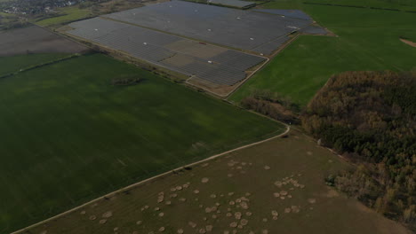 Fields-and-meadows-in-landscape.-Tilt-up-reveal-of-photovoltaic-power-station.-Green-energy,-ecology-and-carbon-footprint-reduction-concept