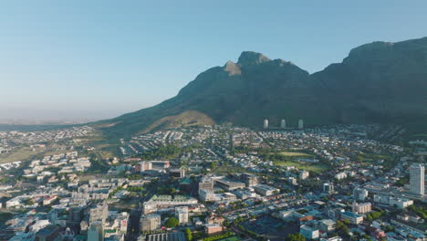 Aerial-panoramic-footage-of-urban-neighbourhood-on-sunny-day.-Rocky-mountain-ridge-in-background.-Cape-Town,-South-Africa