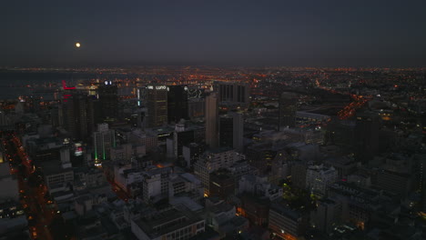 Elevated-panoramic-shot-of-high-rise-buildings-in-city-centre-at-night.-Harbour-in-sea-bay-in-background.-Cape-Town,-South-Africa