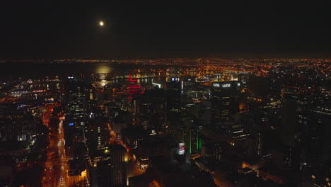 Night-shot-of-high-rise-buildings-in-city-centre-and-harbour-on-sea-coast.-Calm-water-surface-reflecting-moon-shine.-Cape-Town,-South-Africa