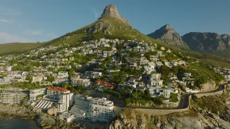 Slide-and-pan-shot-of-luxurious-apartments-in-steep-slope-at-sea-coast.-Mountains-in-background.-Cape-Town,-South-Africa