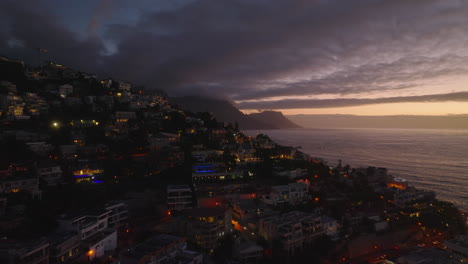 Breath-taking-elevated-footage-of-residential-borough-at-dusk.--Luxurious-residences-in-slope-falling-to-sea-coast.-Cape-Town,-South-Africa