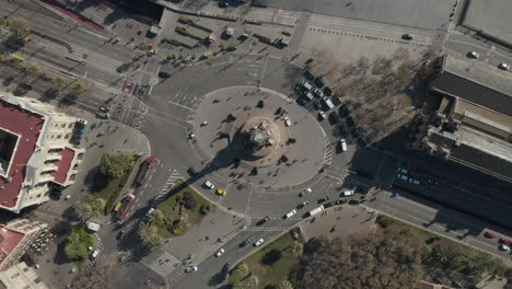 Top-down-rotating-shot-of-square-with-roundabout-around-famous-Columbus-Monument.-Vehicles-passing-road-intersection.-Barcelona,-Spain