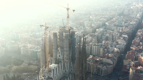 Fly-around-basilica-Sagrada-Familia.-Aerial-view-of-large-unfinished-church-towering-above-city.-Barcelona,-Spain