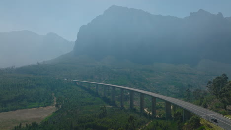 Aerial-view-of-modern-concrete-highway-bridge-over-valley.-Hazy-mountain-ridge-in-background.-South-Africa