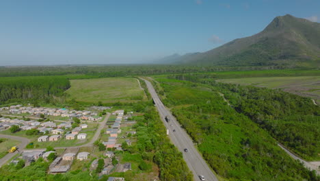 Aerial-footage-of-traffic-on-road-leading-around-village-in-countryside.-Lush-green-vegetation-and-mountain-ridge.-South-Africa