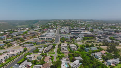 Slide-and-pan-aerial-shot-of-buildings-and-streets-in-town.-Apartment-houses-and-residences-from-height.-Plettenberg-Bay,-South-Africa