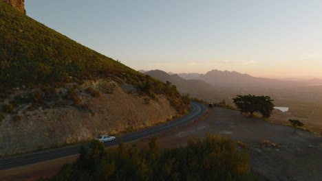 Fly-around-mountain-ridge.-Tracking-of-car-driving-on-road-in-countryside-in-sunset-time.-South-Africa