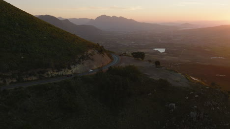 Amazing-footage-of-cars-driving-on-mountain-road-in-landscape-lit-by-setting-sun.-Mountain-ridges-in-distance.-South-Africa