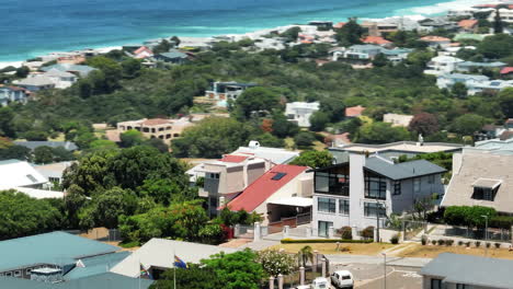 Slide-and-pan-aerial-footage-of-houses-in-elevated-urban-borough.-Parallax-effect.-Sea-coast-in-summer-vacation-destination.-South-Africa