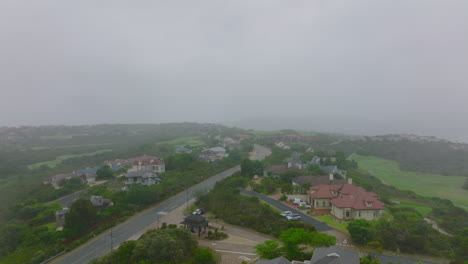 Large-family-houses-and-residencies-along-road-in-residential-suburb.-Forwards-fly-above-misty-landscape.-Port-Elisabeth,-South-Africa