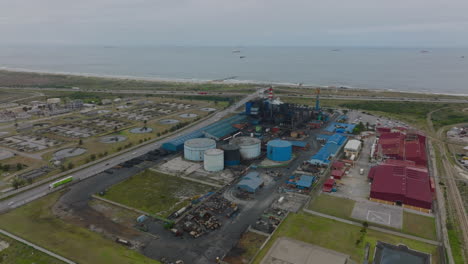 Slide-and-pan-aerial-footage-of-factory-and-wastewater-treatment-site-near-sea-coast.-Port-Elisabeth,-South-Africa
