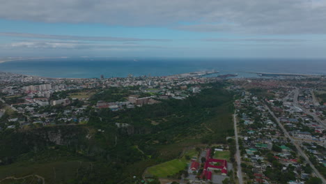 Aerial-view-of-green-valley-with-river-between-urban-neighbourhoods-and-sea-in-background.-Port-Elisabeth,-South-Africa