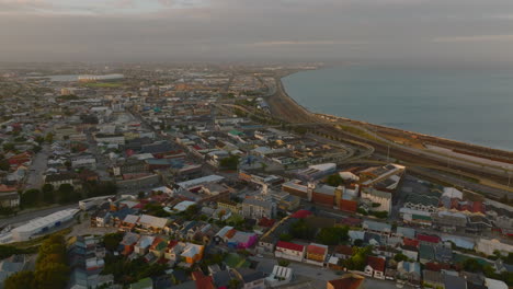 Fly-above-town-at-dusk.-Aerial-descending-footage-of-development-along-sea-coast.-Port-Elisabeth,-South-Africa