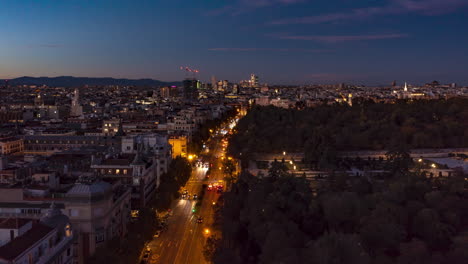 Forwards-fly-above-large-city-at-twilight.-Busy-multilane-road-leading-along-El-Retiro-Park.-Hyperlapse-footage-with-gradually-dimming-sky.-Madrid,-Spain